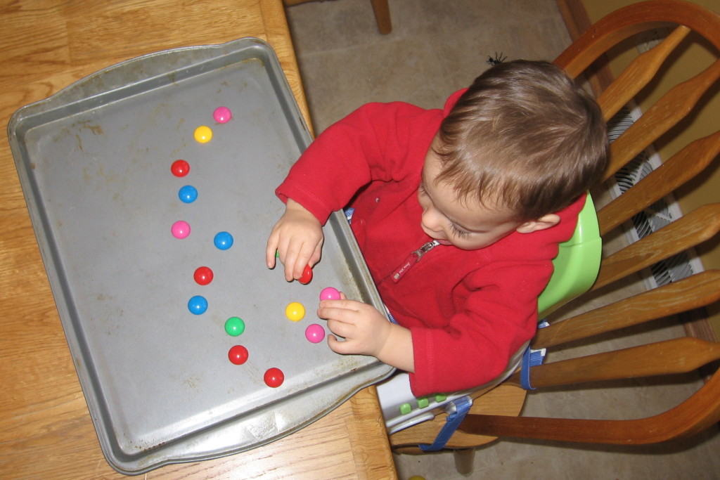child placing magnets on baking sheet