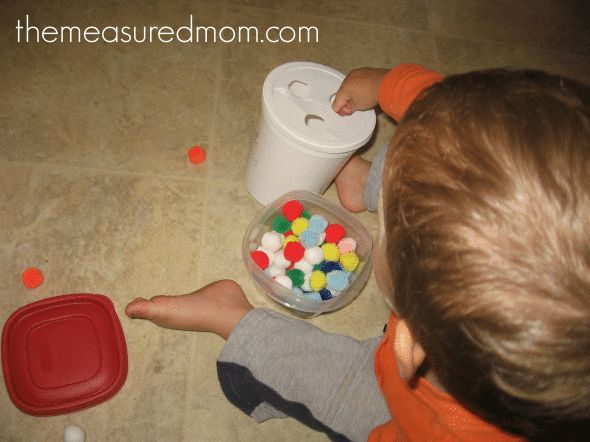 Looking for activities for one year olds? These 5 toddler activities kept our 18 month old busy and happy!  child poking pom-poms through holes