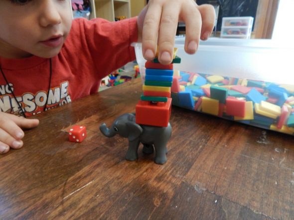 Roll the die and add that many tiles to the elephant's back. How many can you add until the stack falls?